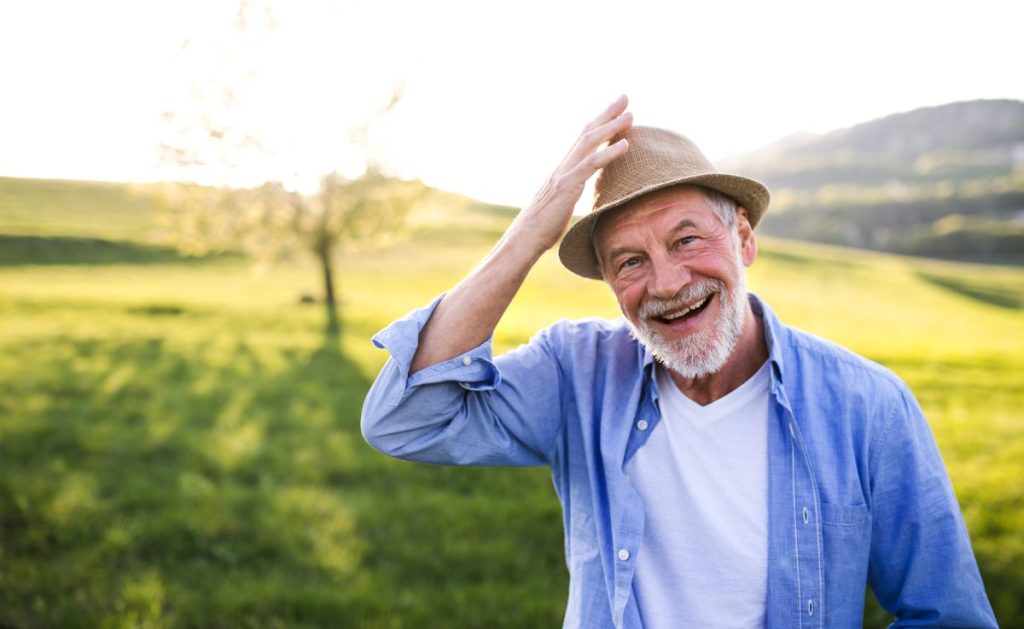 Elderly man holding his hat.